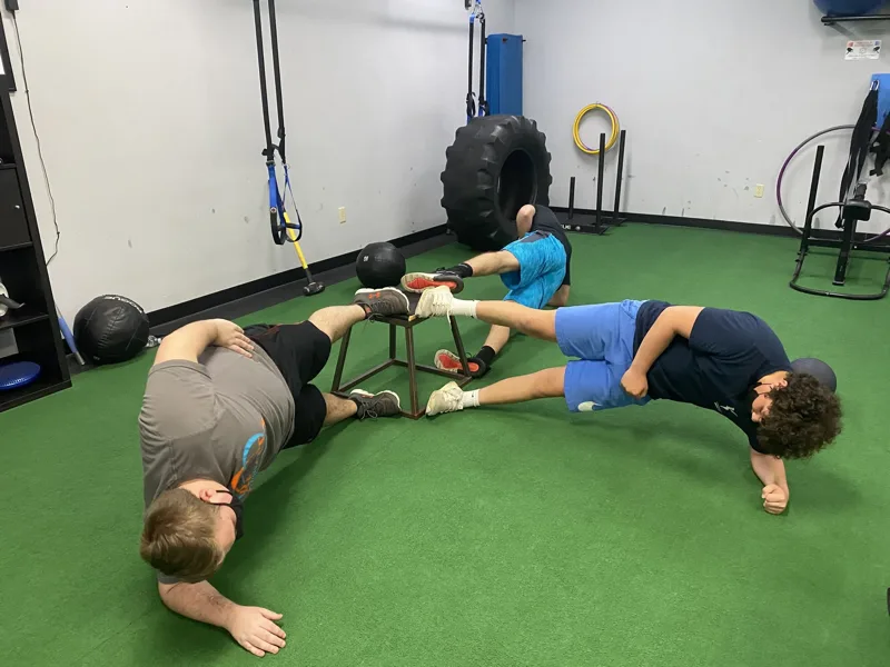 Members doing a partner stretch exercise on the turf