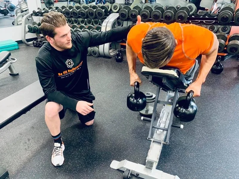 Coach guiding a member through a kettlebell exercise at Be Fit Performance Center